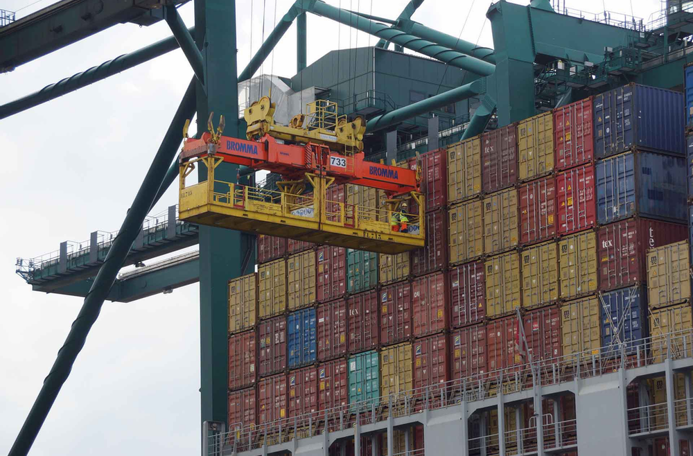 Workers on a crane trolley preparing to unload containers