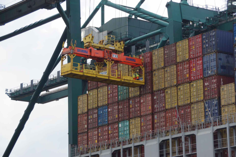 Workers on a crane trolley preparing to unload containers