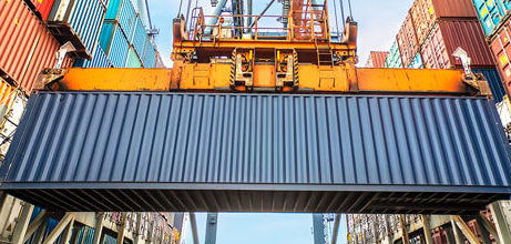 Dock crane moving a container with containers stacked on both sides