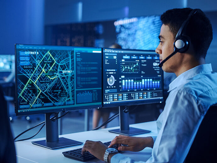 Man with headset monitoring two computer screens